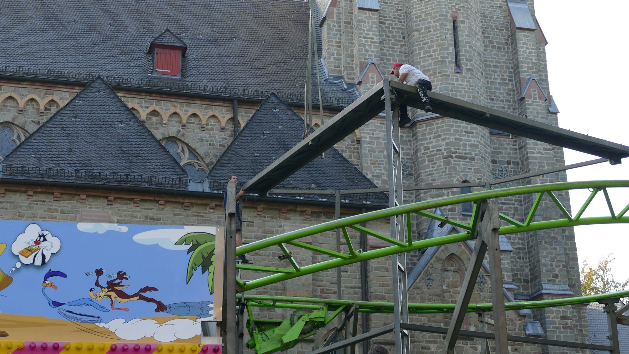Arbeiter bauen die Achterbahn Speedy Gonzalez vor der Kirche St. Patricius zusammen.