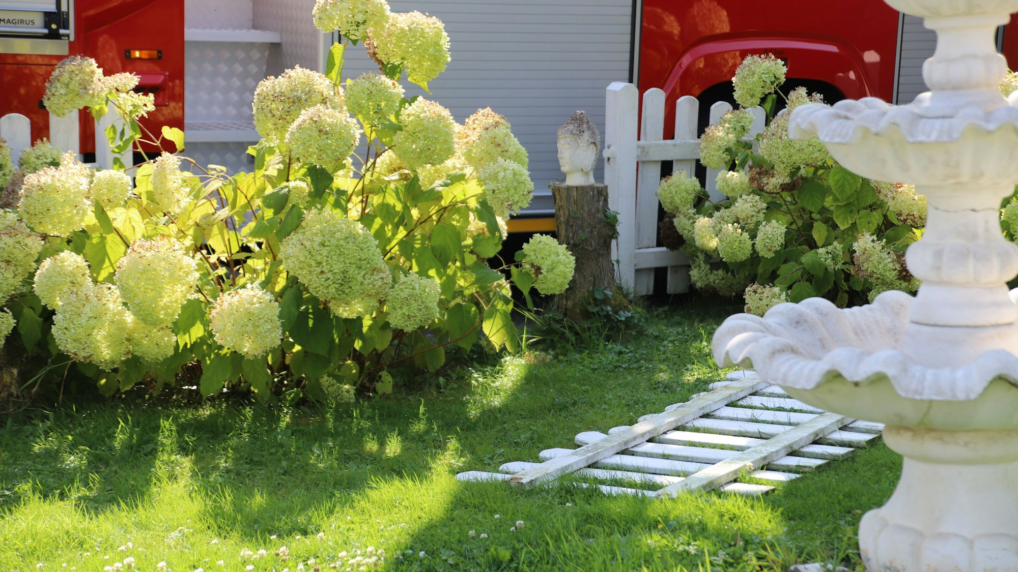 Ein Feuerwehrfahrzeug steht hinter einem Zaun, ein Teil davon liegt daneben..