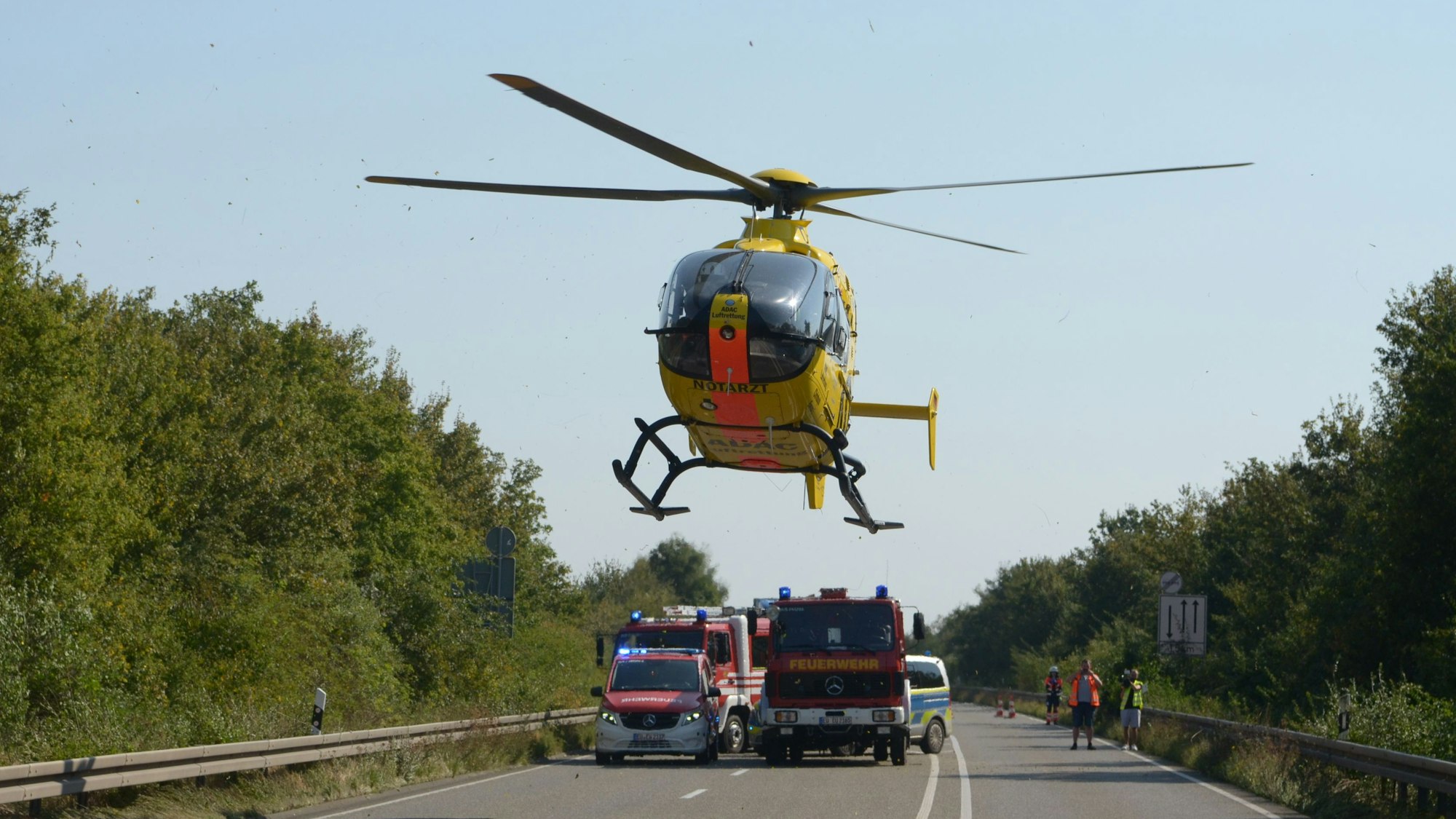 Ein gelber Rettungshubschrauber des ADAC landet auf einer Straße bei Zülpich.