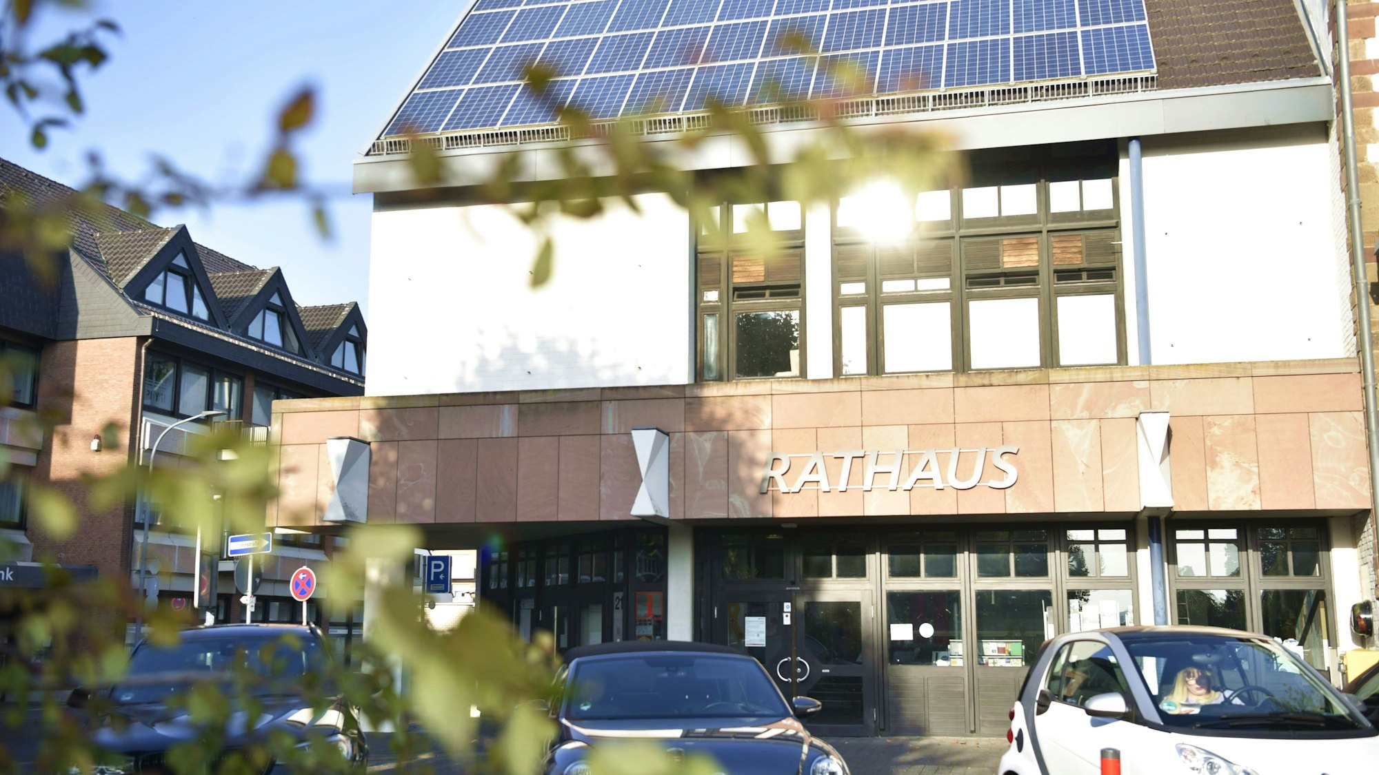 Die Abendsonne spiegelt sich in den Fenstern des Zülpicher Rathauses, davor parken ein paar Autos.