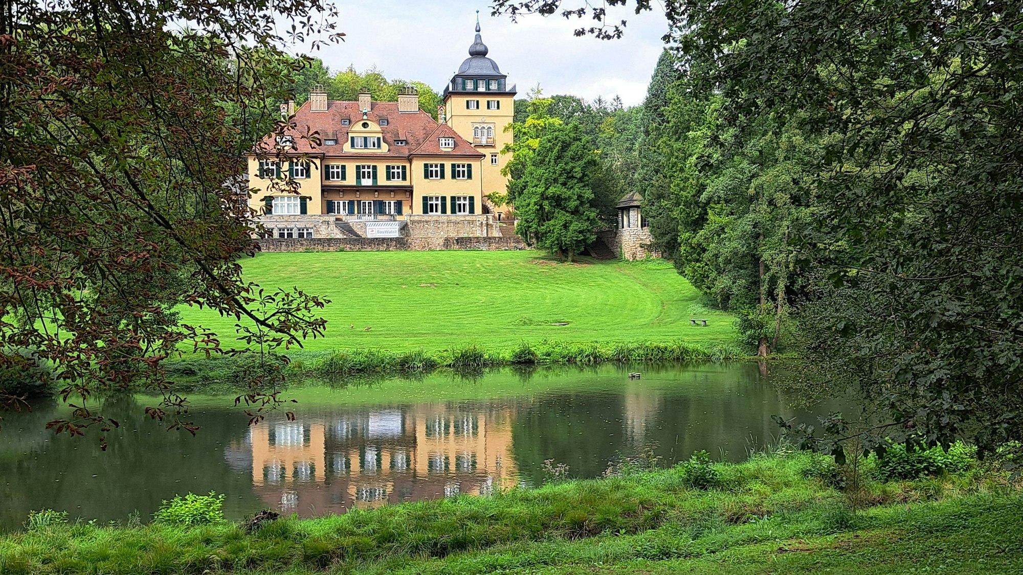 Schlosshotel Lerbach ist samt Spiegelbild im Teich der Parkanlage zu sehen.