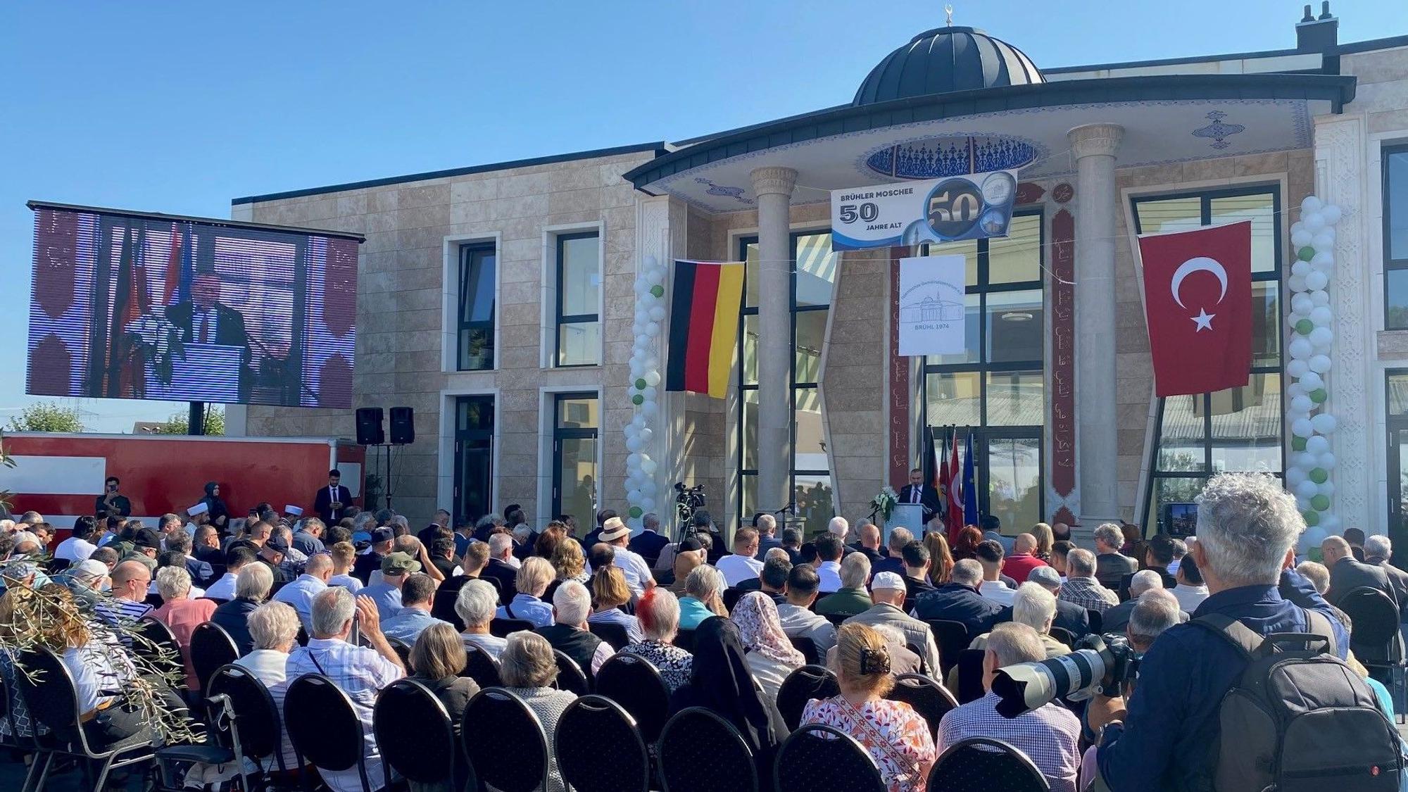 Zu sehen sind vollbesetzte Stuhlreihen vor der neuen Moschee.