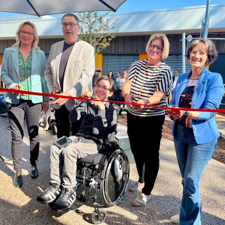 Fünf Menschen durchschneiden ein rotes Band.