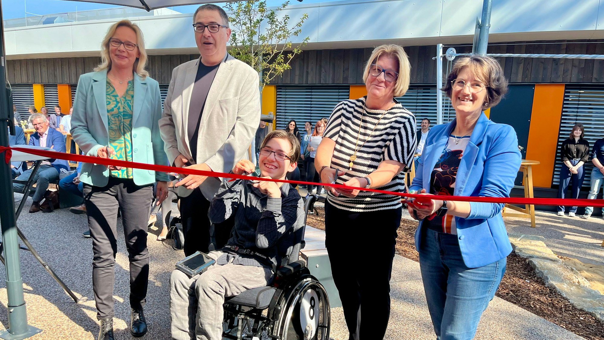 Fünf Menschen durchschneiden ein rotes Band.