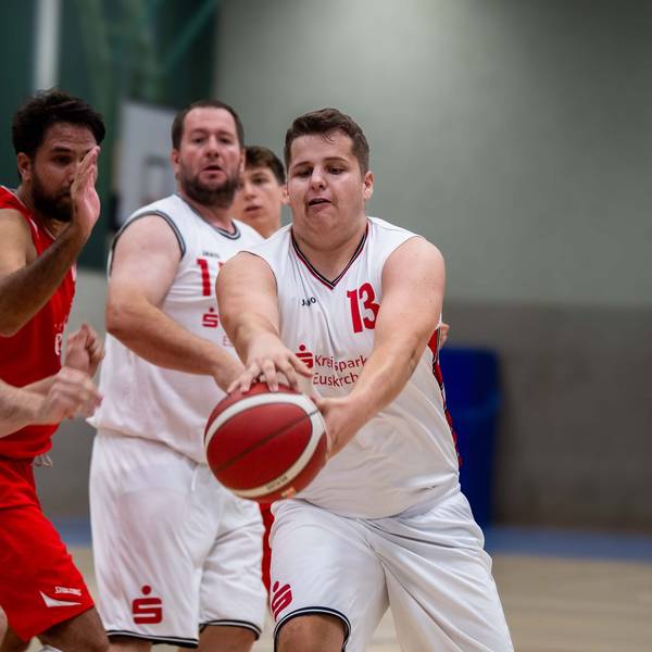 Ein Basketballspieler aus Zülpich greift während eines Testspiels nach dem Ball. Mitspieler und Gegenspieler schauen zu.