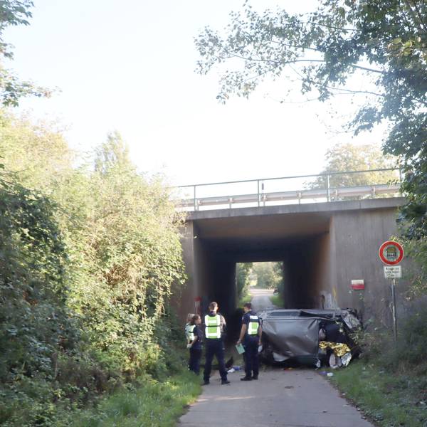 Auf dem Foto stehen Polizistinnen und Polizisten vor dem Autowrack.