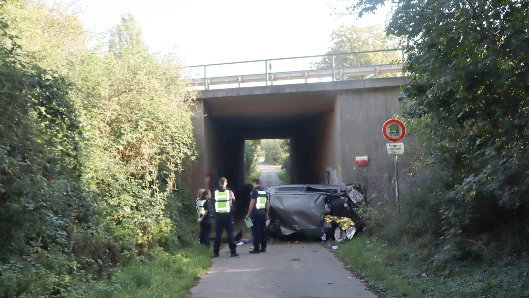 Auf dem Foto stehen Polizistinnen und Polizisten vor dem Autowrack.