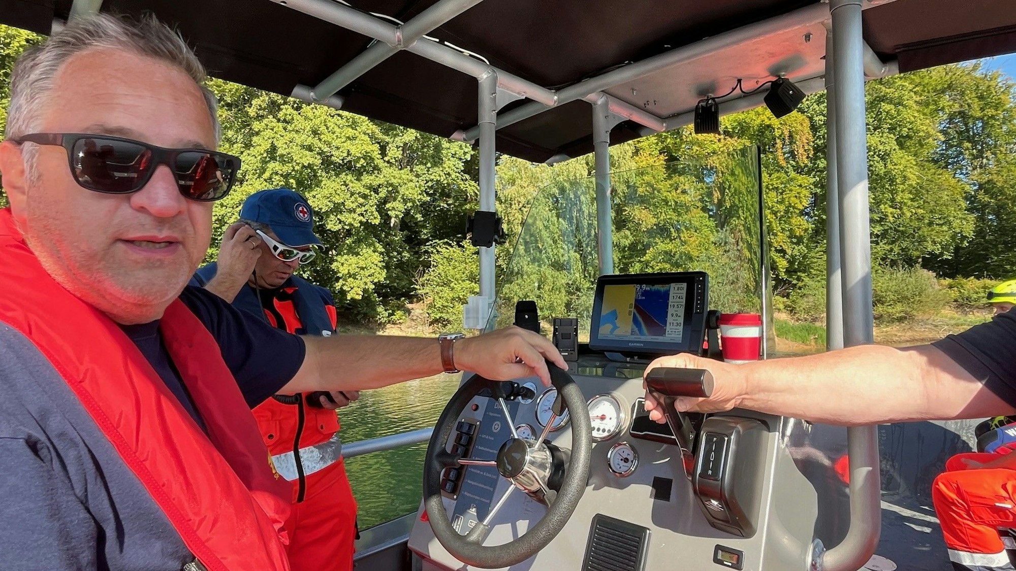 Ein Mann bedient das Steuer eines Bootes.