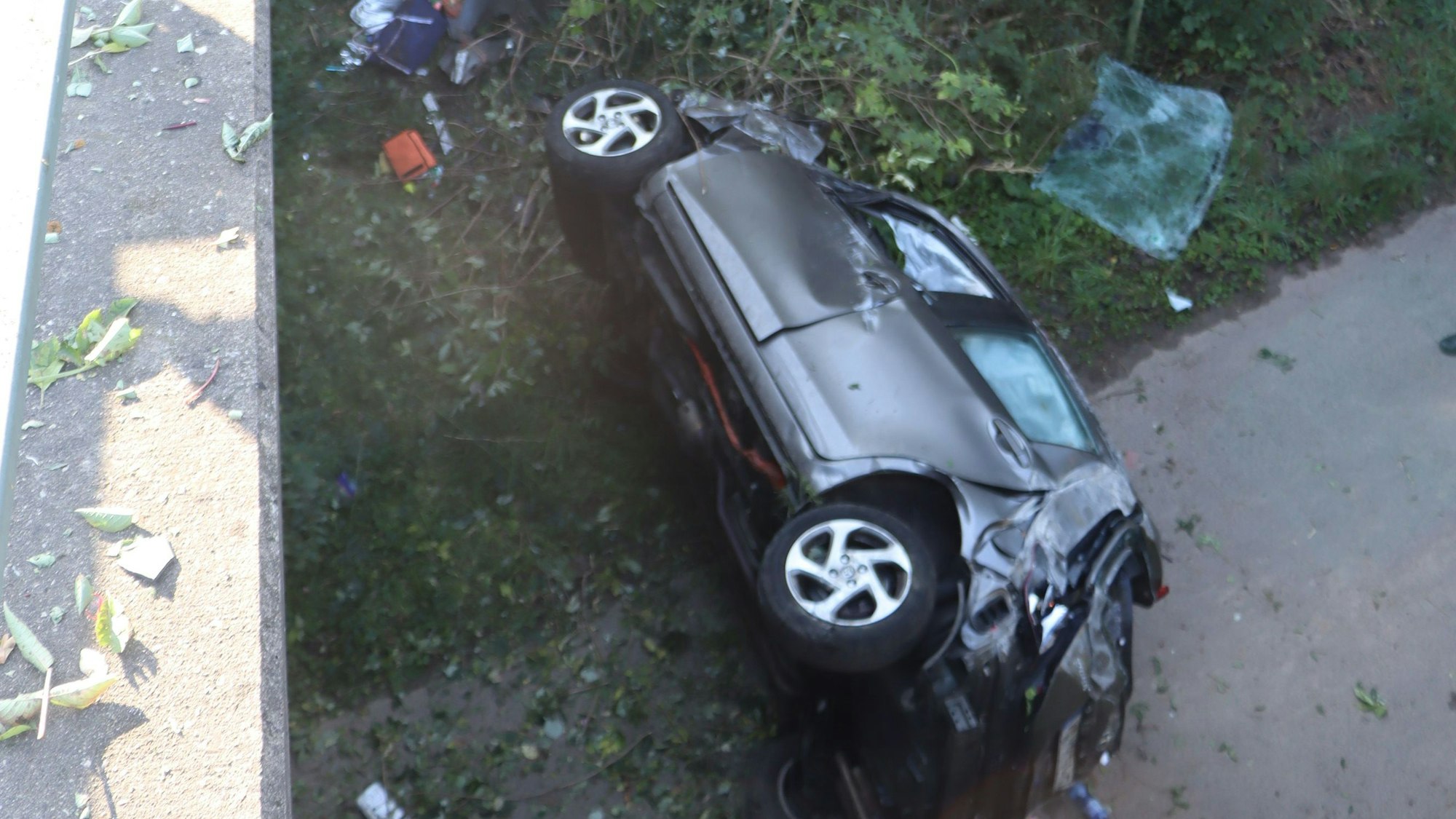 Das Bild zeigt einen auf der Seite liegenden Pkw unter einer Autobahnbrücke.
