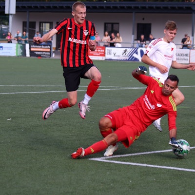 Ein Fußballer springt über den Torwart, um ihn nicht zu verletzen.