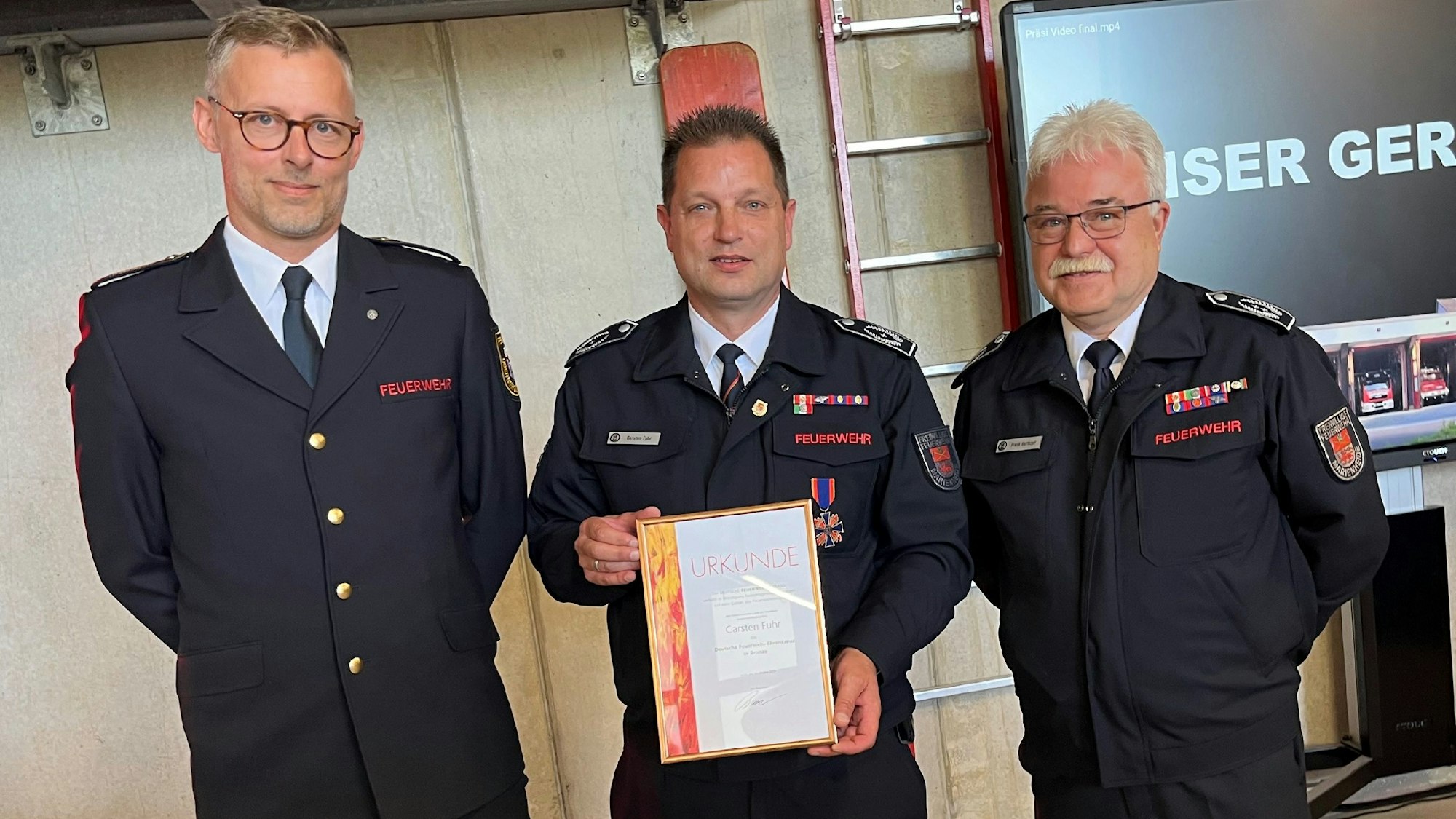 Carsten Fuhr (Mitte.), Stellvertretender Feuerwehrchef in Marienheide, erhielt von Kreisbrandmeister Julian Seeger (links.) im Beisein vom Leiter der Feuerwehr, Frank Hartkopf, das Feuerwehrehrenkreuz in Bronze.