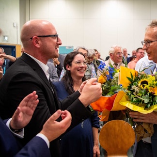 Ingo Pfennings steht neben Detlef Seif, der einen Blumenstrauß in der Hand hält.