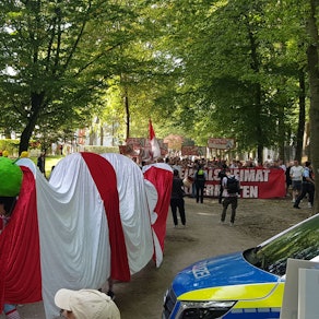 Protest der Bürgerinitiative Grüngürtel für Alle am Geißbockheim gegen den Bau des Jugendleistungszentrums.
Im Hintergrund stören etwa 150 Ultras durch Gesänge den Spaziergang der Ausbaugegner.