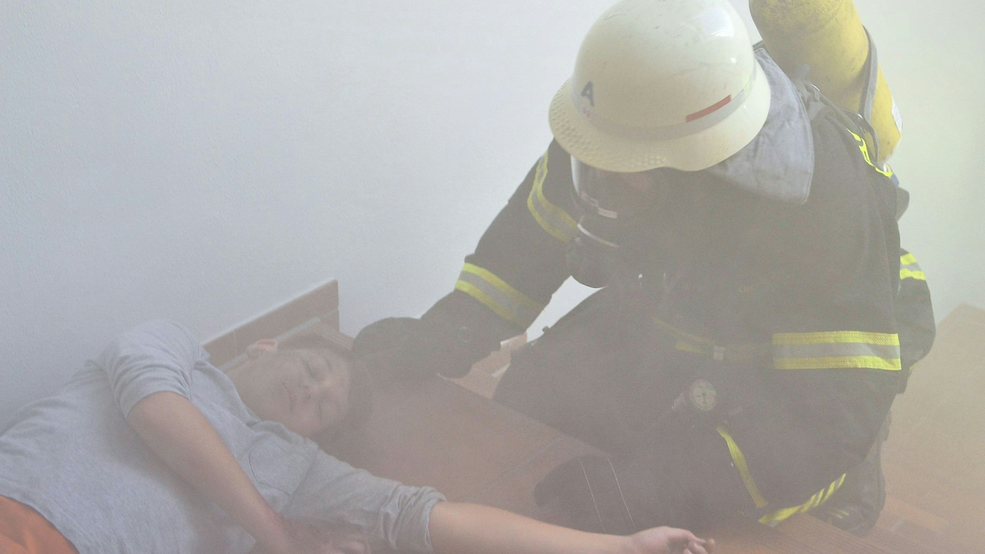 Im dichten Qualm einer Nebelmaschine liegt ein Verletzten-Darsteller am Boden und wird von den Rettungskräften in Sicherheit gebracht.