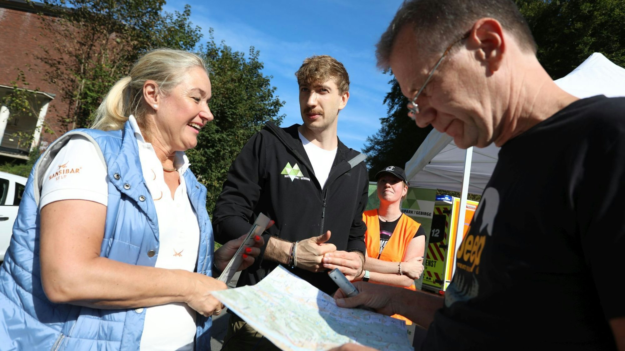 Menschen stehen zusammen, einer hält eine Landkarte.