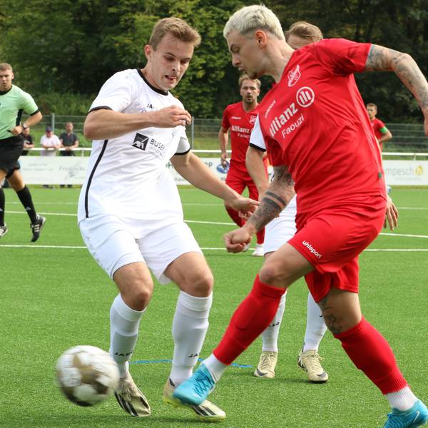 Ein Fußballspieler legt den Ball an seinem Gegner vorbei.