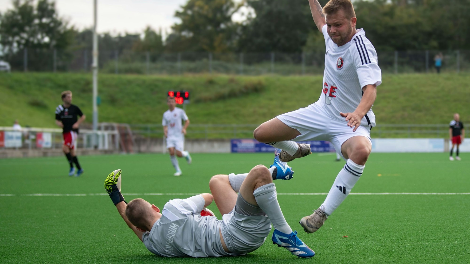Ein Fußballer springt über den Torwart.