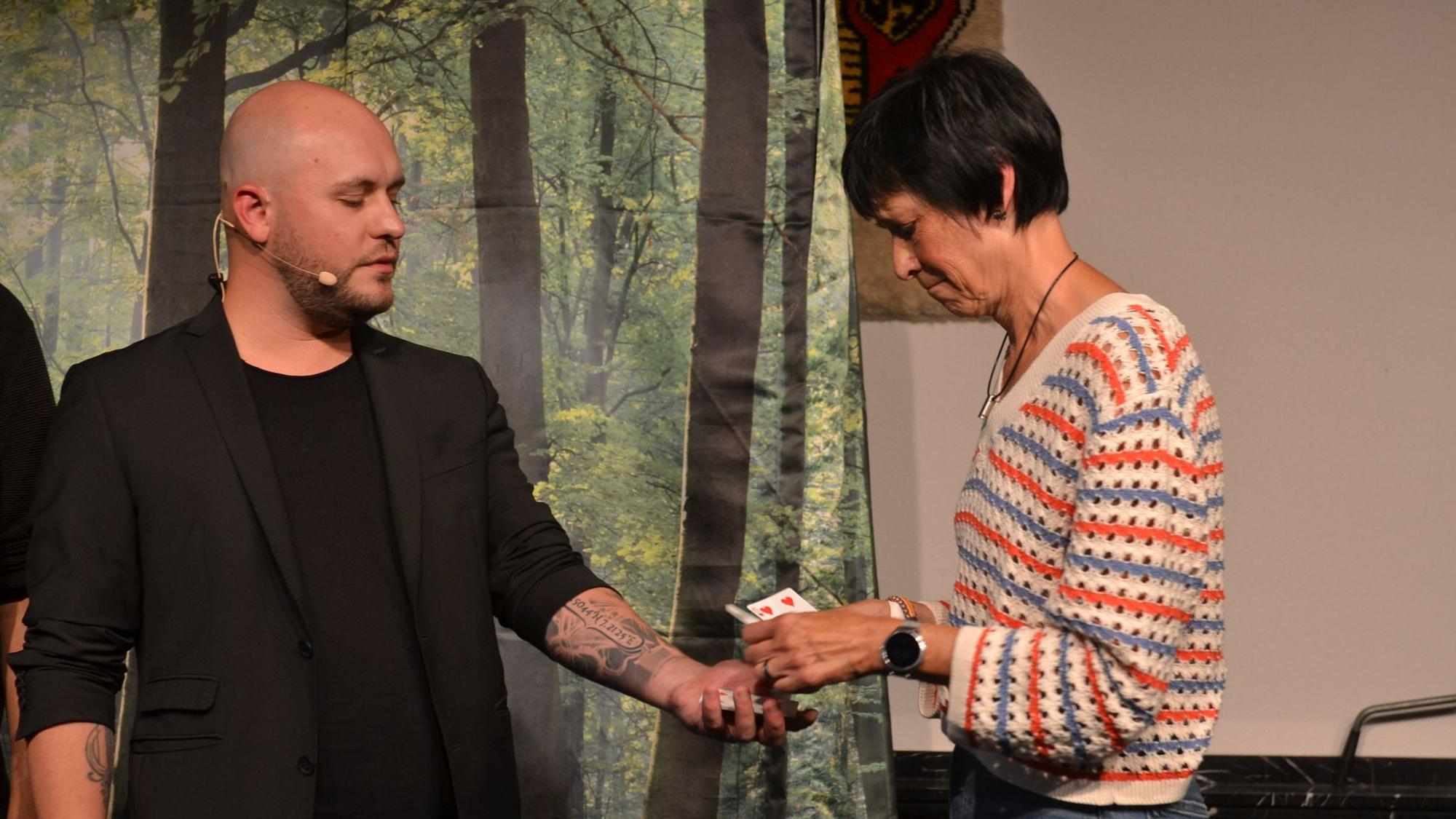 Luke Dimon macht einen Zaubertrick mit Karten mit einer Besucherin.