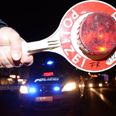 Eine Haltekelle der Polizei ist bei einer Alkoholkontrolle vor einem Polizeifahrzeug zu sehen.