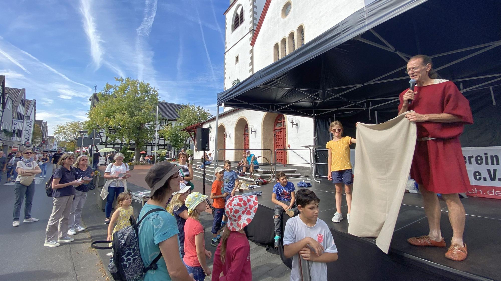 "Eine römische Toga ist ein viereckiges Stück Stoff mit vier Löchern." Die römische Kleidung erklärte kindgerecht Museumspädagoge Kai-Ingo Weule vom Römerkanal-Informationszentrum. Auf der Bühne vor der katholischen Pfarrkirche St. Martin hatten die Veranstalter Alt und Jung zu einer Mitmach-Modenschau eingeladen.