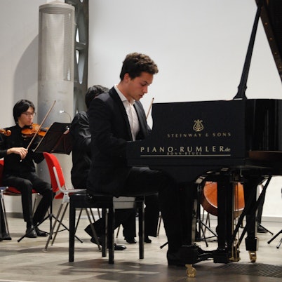 Nikola Meeuwsen am Klavier, im Hintergrund sind zwei Streicher des Folkwang Orchesters zu sehen.