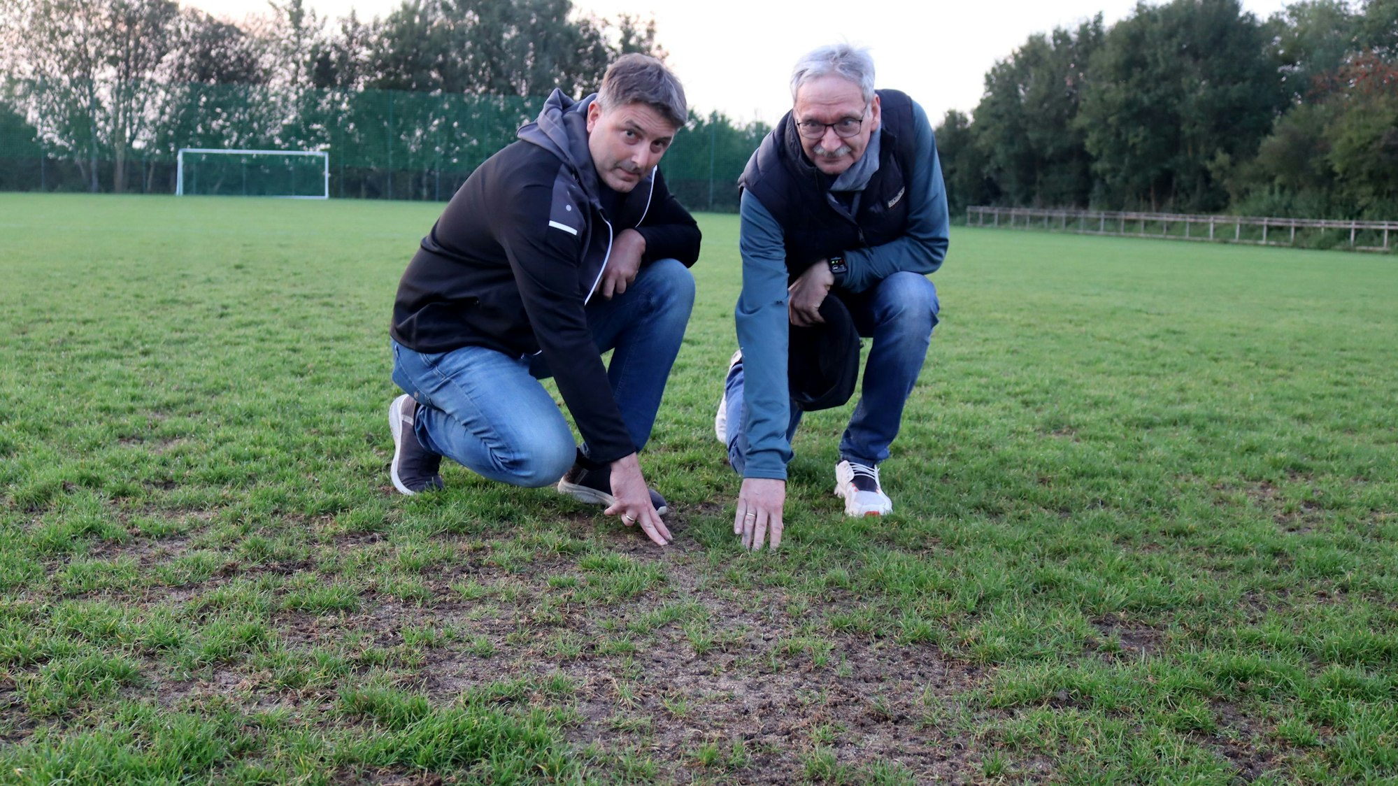 Auf graslose Stellen und Stolperfallen im Rasenplatz deuten Jugendleiter Sascha Franke (l.) und Vorsitzender Hans-Wilhelm Garrelfs.