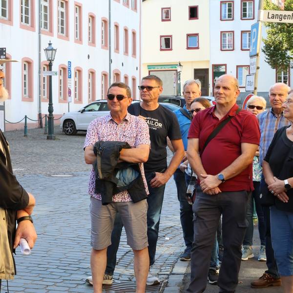 Stadthistoriker Harald Bongart trägt einen hellen Hut. Er steht auf einem Platz in Bad Münstereifel vor einer Gruppe von Männern und Frauen, die ihm zuhören.