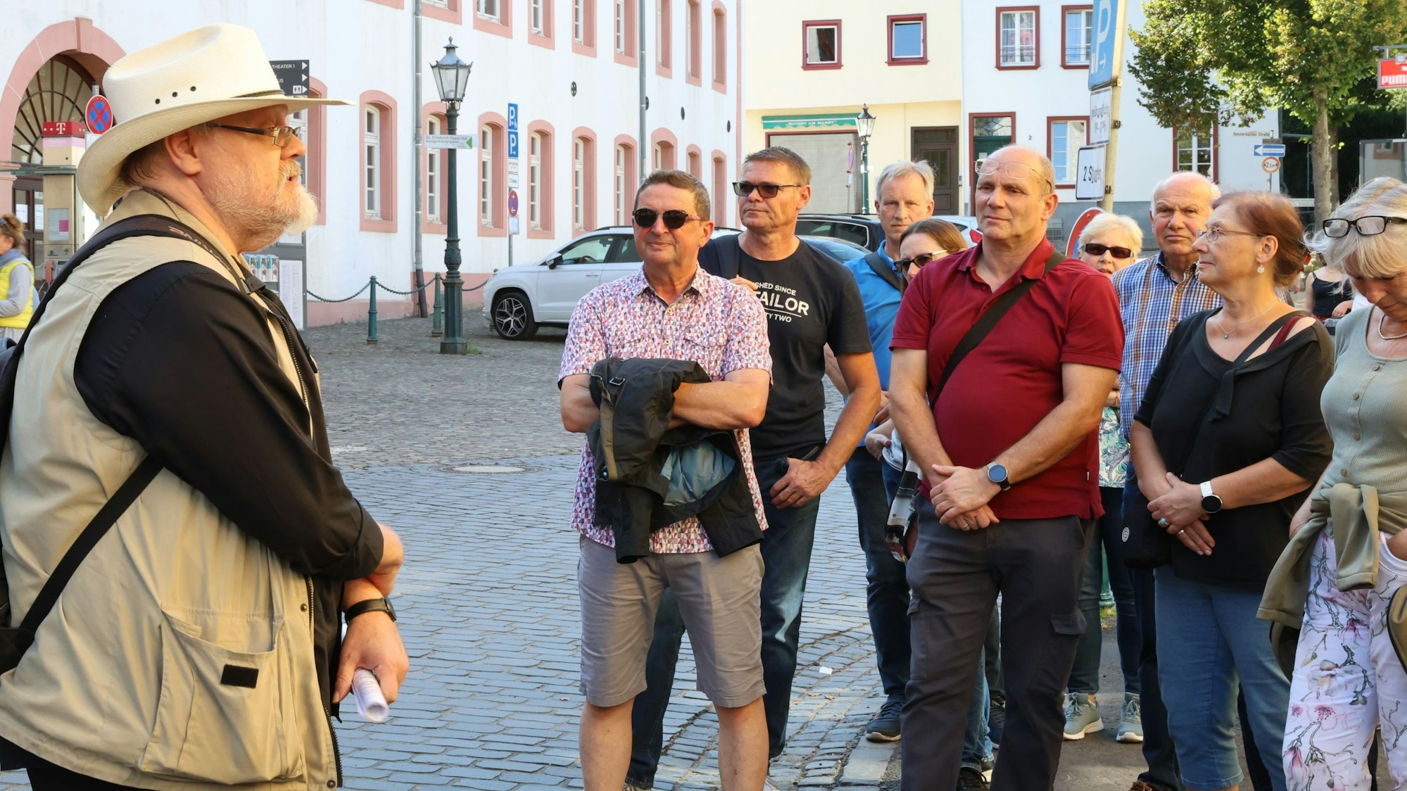 Stadthistoriker Harald Bongart trägt einen hellen Hut. Er steht auf einem Platz in Bad Münstereifel vor einer Gruppe von Männern und Frauen, die ihm zuhören.