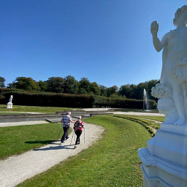 Zu sehen sind zwei Spaziergänger vor der Großen Fontäne im Schlosspark.
