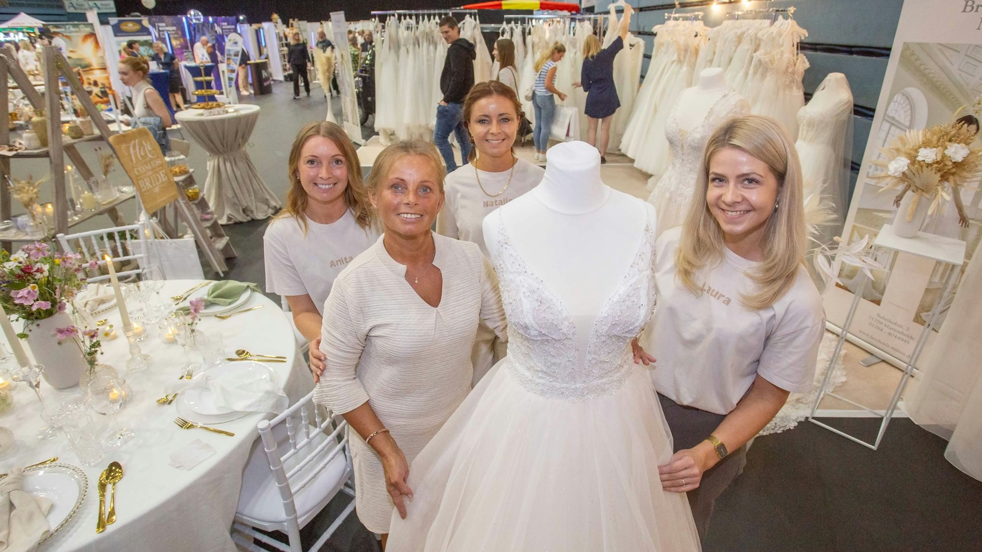 Das Foto zeigt vier Frauen an einem Stand mit Hochzeitskleidern.