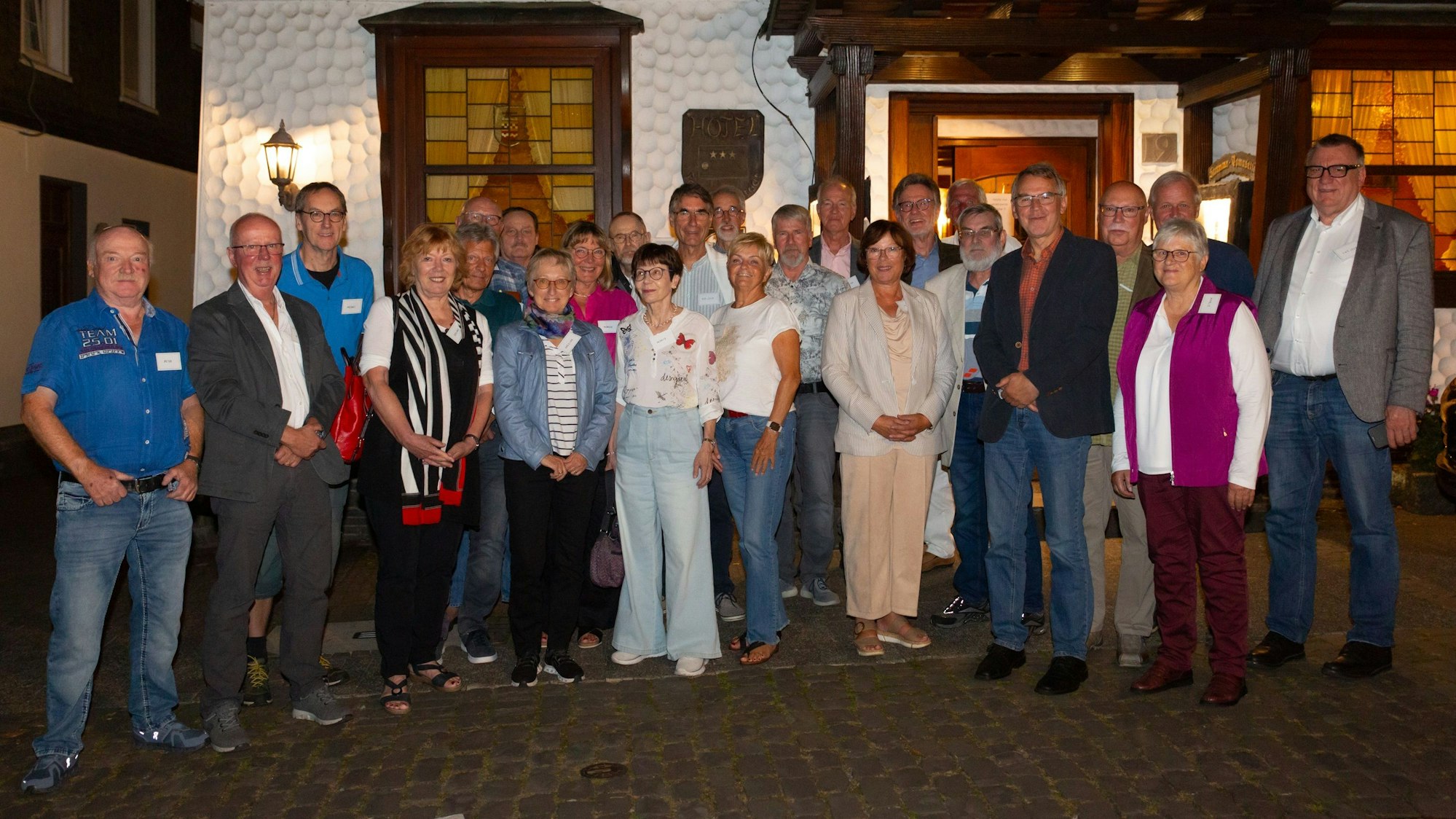 Eine Gruppe Männer und Frauen steht zum Foto aufgestellt vor dem Eingang des Restaurants Feste Neustadt.