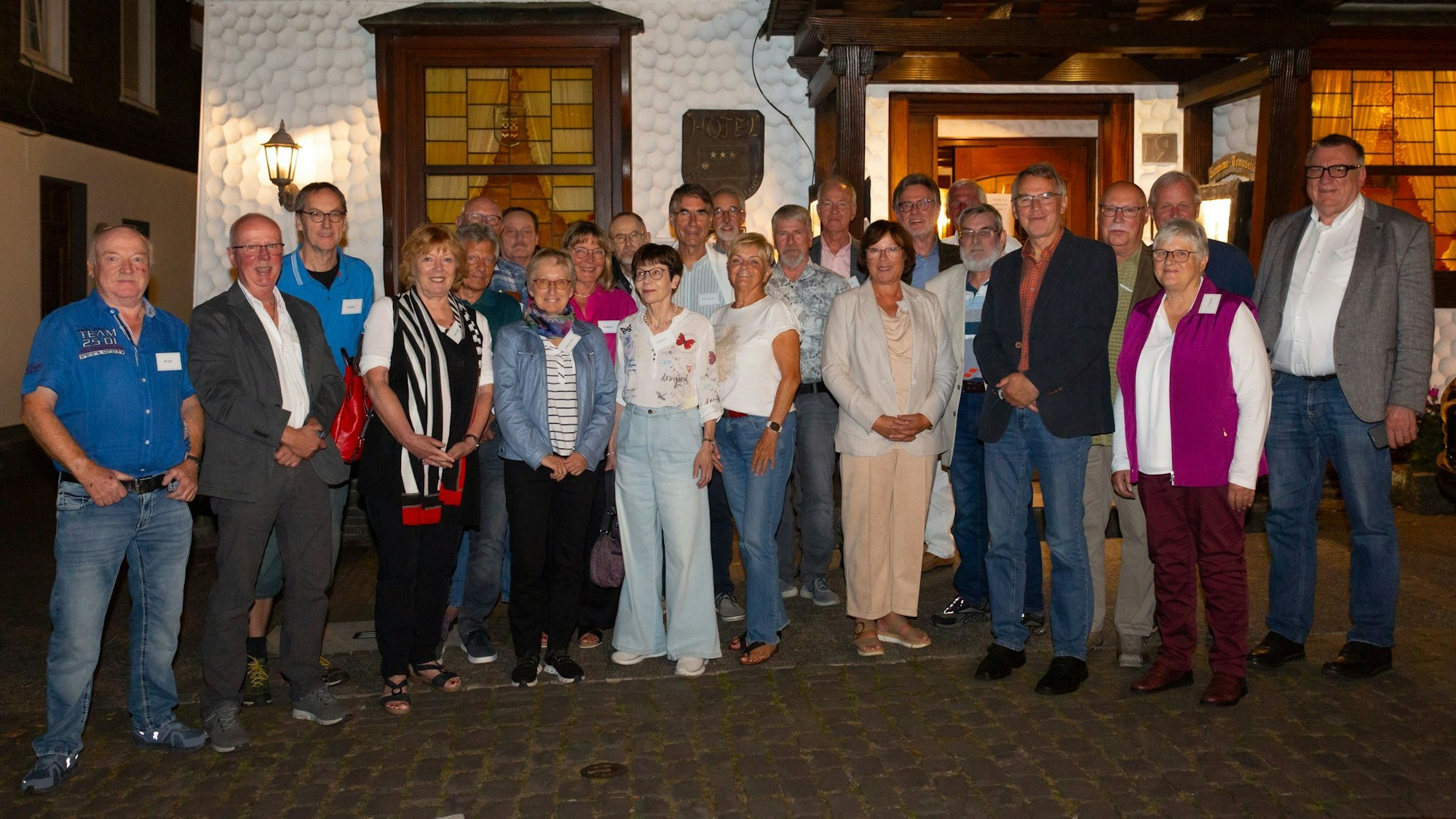 Eine Gruppe Männer und Frauen steht zum Foto aufgestellt vor dem Eingang des Restaurants Feste Neustadt.
