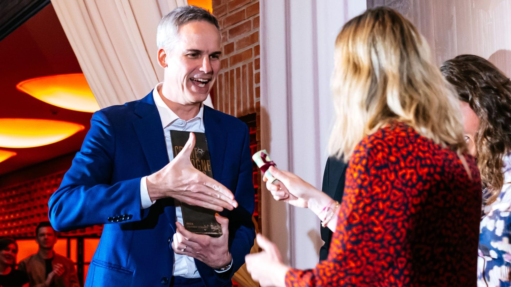 Stephan Schmidt hält seinen Award und bekommt ein Geldbündel überreicht.