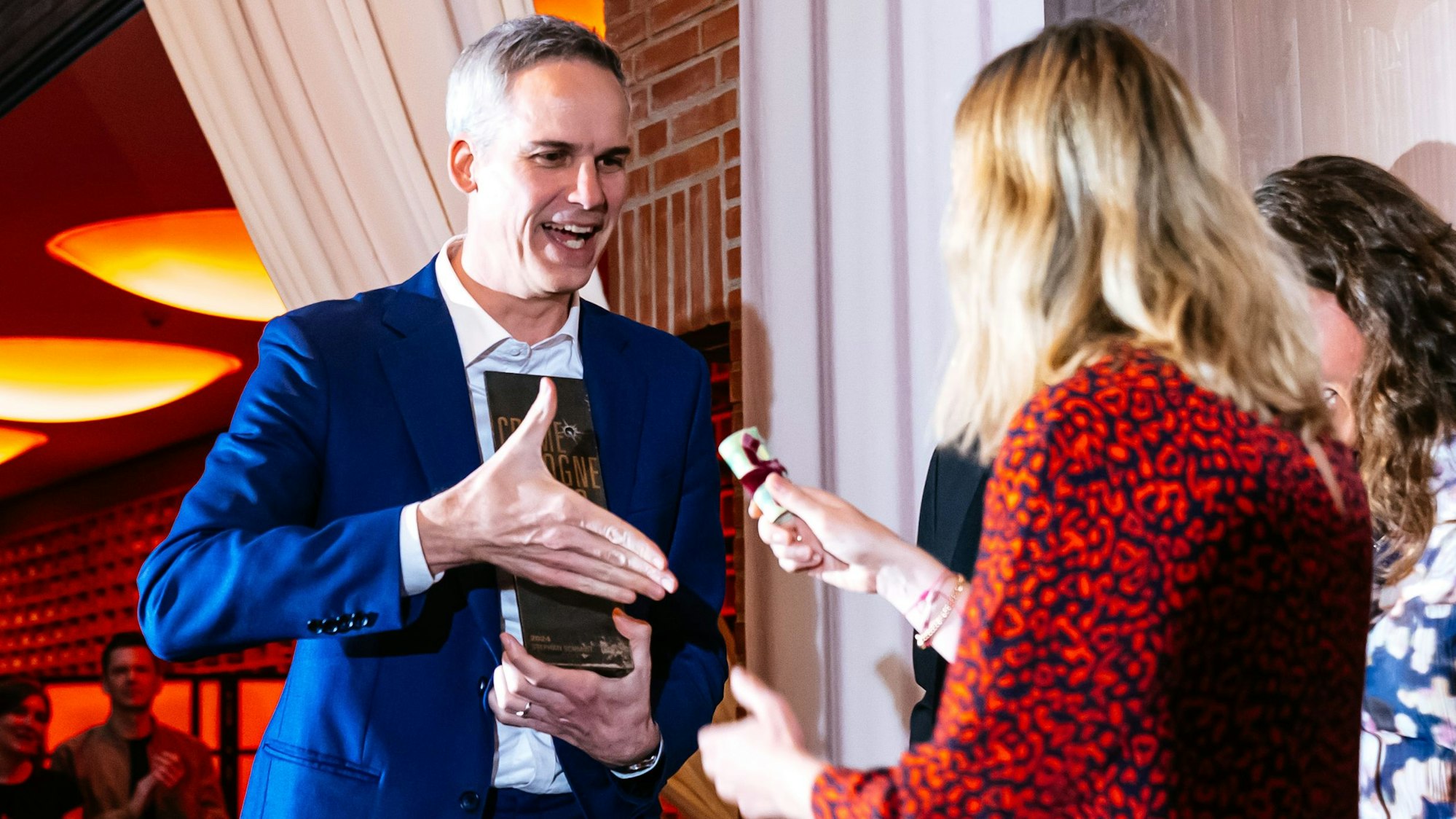 Stephan Schmidt hält seinen Award und bekommt ein Geldbündel überreicht.