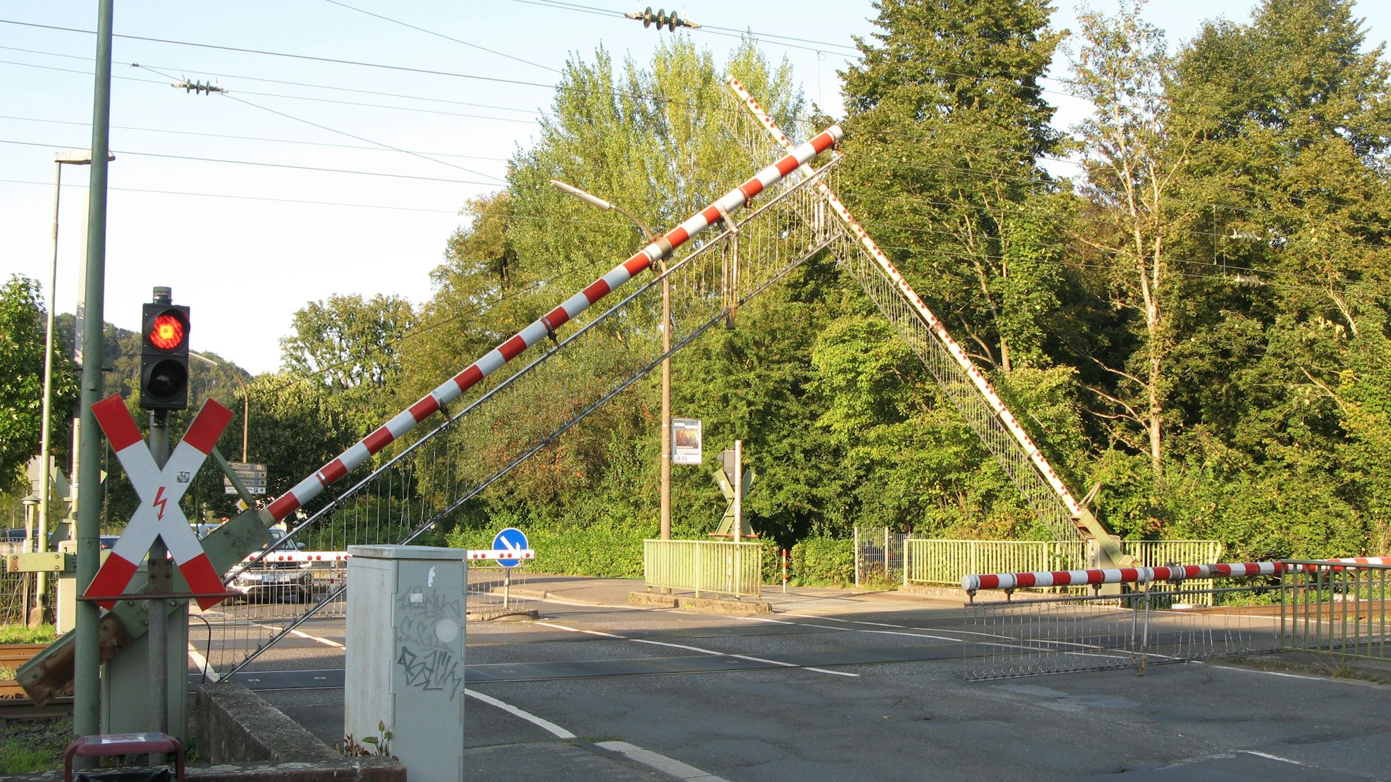 Die Schranken senken sich an einem Bahnübergang.
