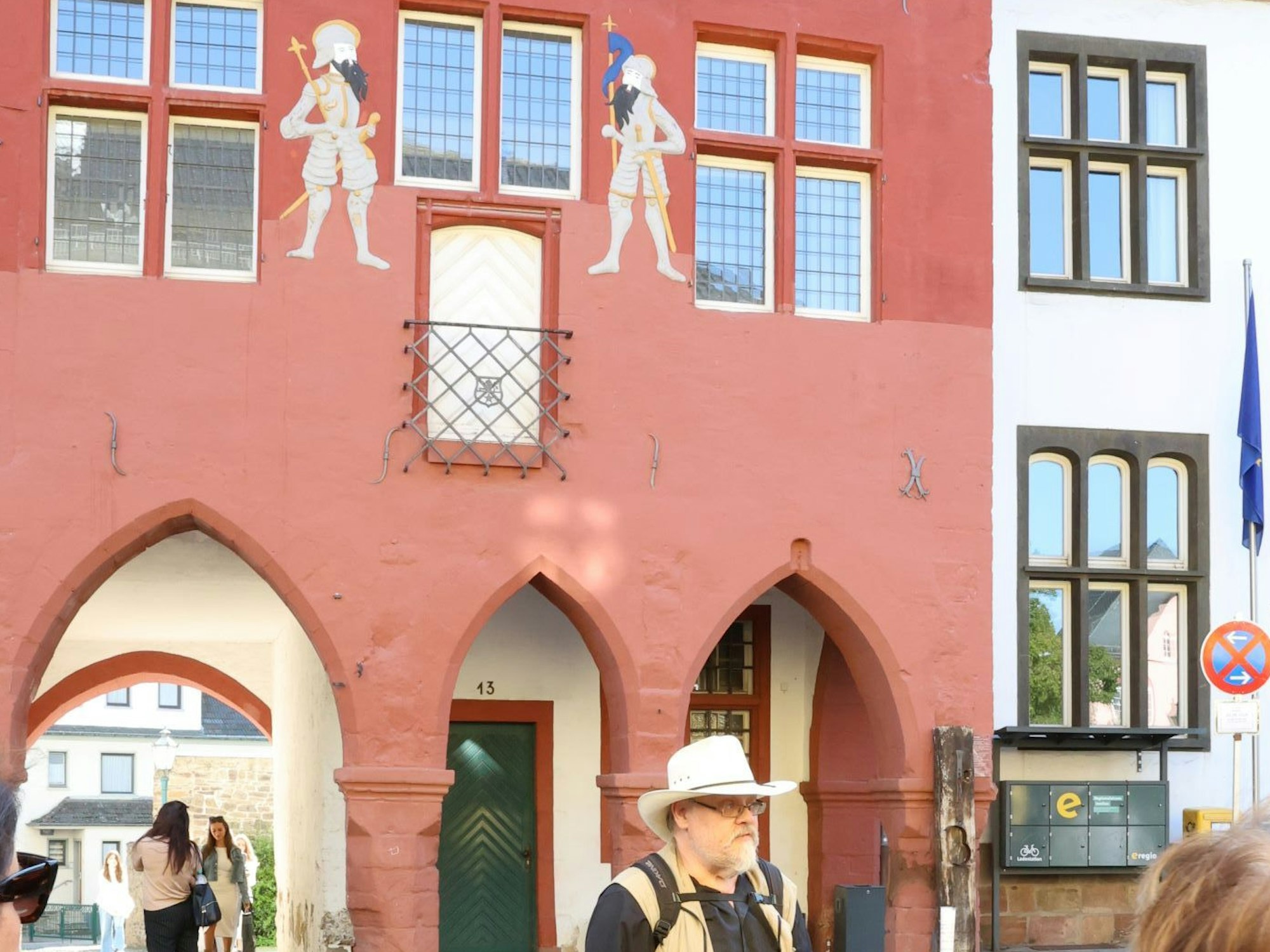 Ein Mann mit hellem Hut steht vor dem Rathaus in Bad Münstereifel. Oberhalb der Torbögen ist eine weiße Tür zu sehen.