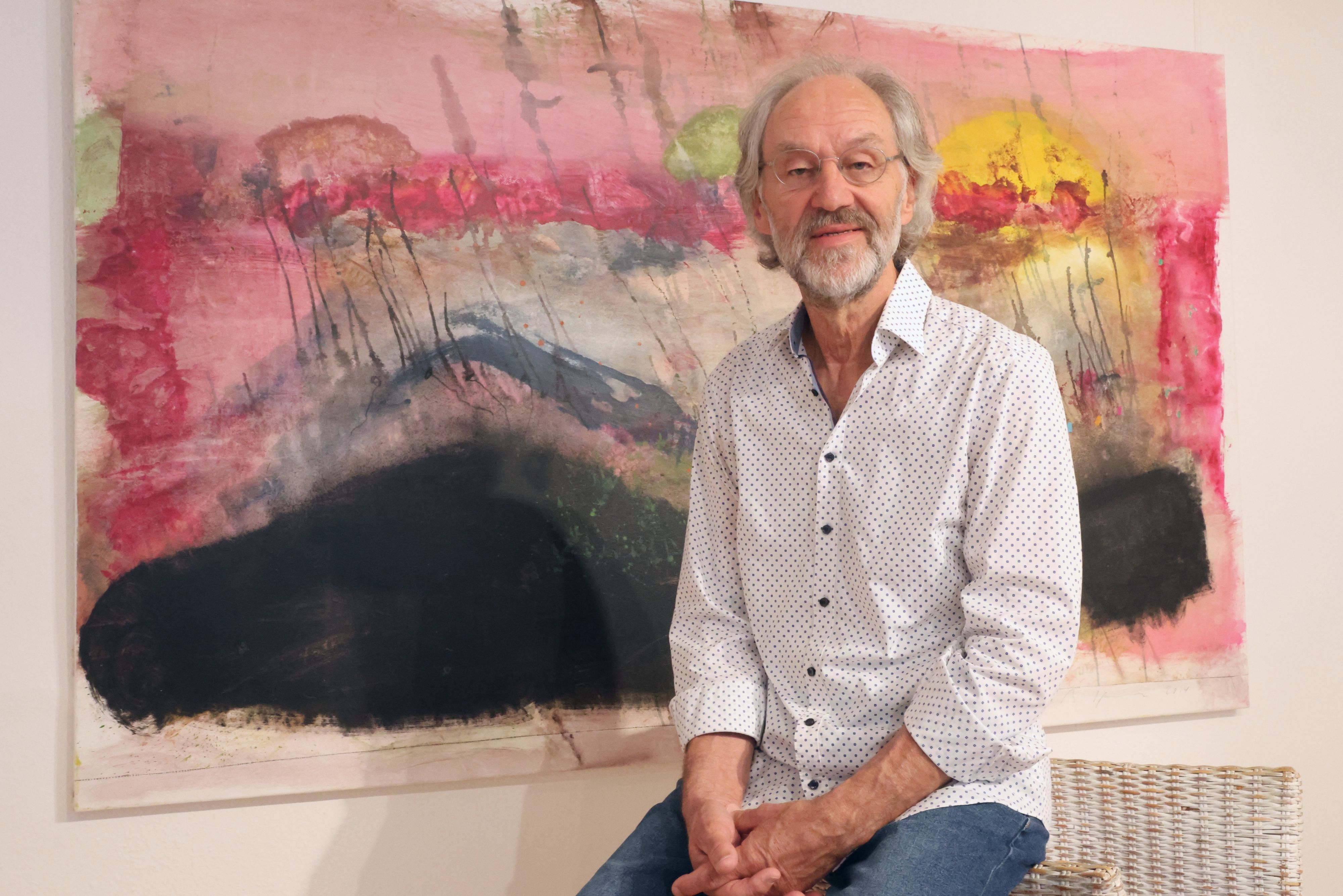 Der Künstler Bruno Obermann ist vor einem großformatigen Gemälde zu sehen, Das Bild trägt den Titel „Tod nach drei Religionen“.