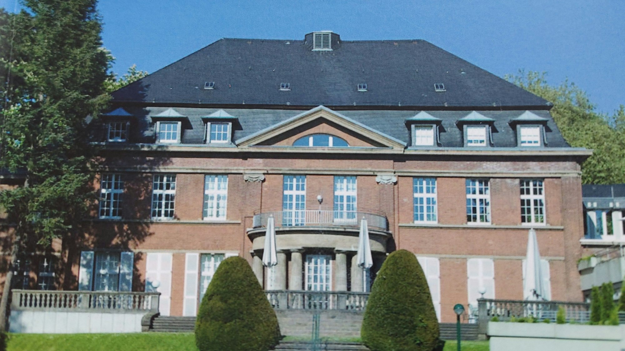 Villa Risch von der Gartenseite. Ein herrschaftlicher Bau mit Walmdach und großer Terrasse.