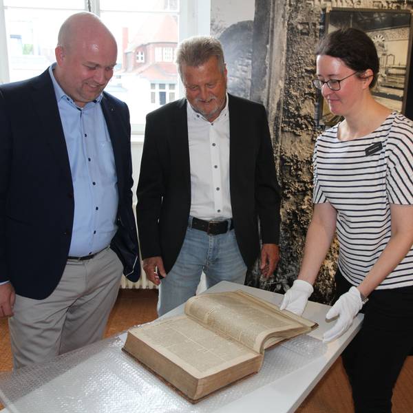 Zwei Männer und eine Frau mit einem historischen Buch