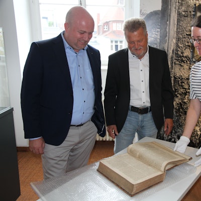 Zwei Männer und eine Frau mit einem historischen Buch