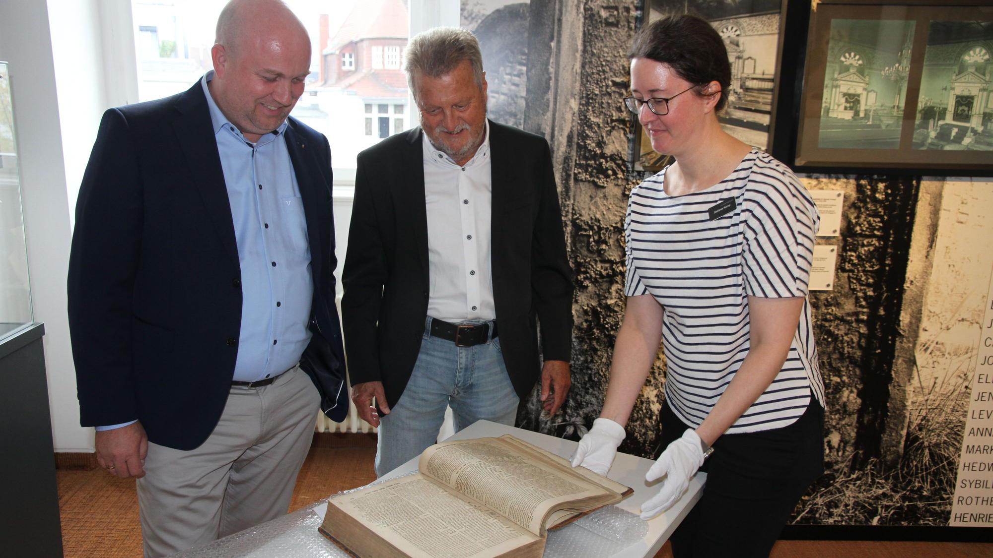 Zwei Männer und eine Frau mit einem historischen Buch