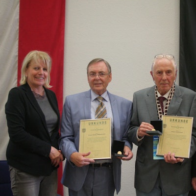 Auf dem Bild sind eine Frau und drei Männer bei einer Ehrung in feierlichem Rahmen zu sehen.