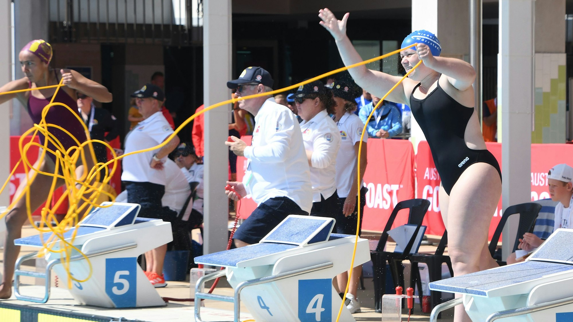 Die Ripsdorferin Eva Hoetgen steht bei der Rettungsschwimmen-WM in Australien im schwarzen Badeanzug und blauer Badekappe am Beckenrand und wirft ein gelbes Seil, drumherum stehen Leute.