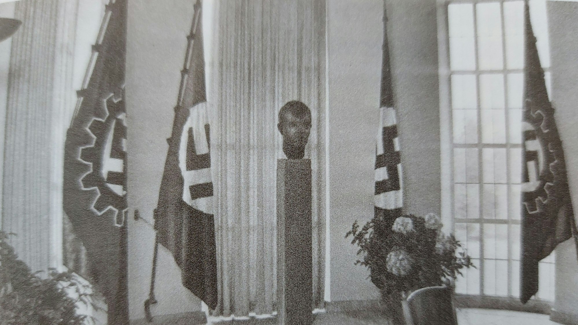 Historisches Foto: Ein Raum mit Hitler-Büste und Hakenkreuz-Fahnen.