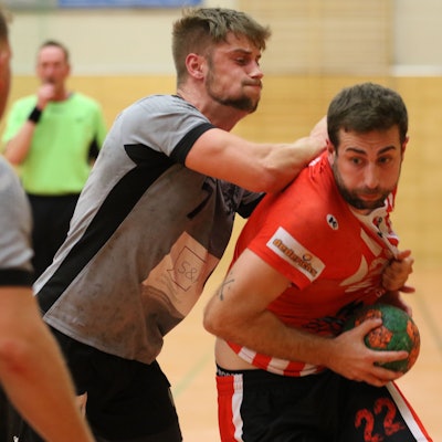 Euskirchens David Henzel hält den Ball vor seinem Bauch. Von hinten stößt ihn ein Gegenspieler mit dem Arm gegen den Rücken.
