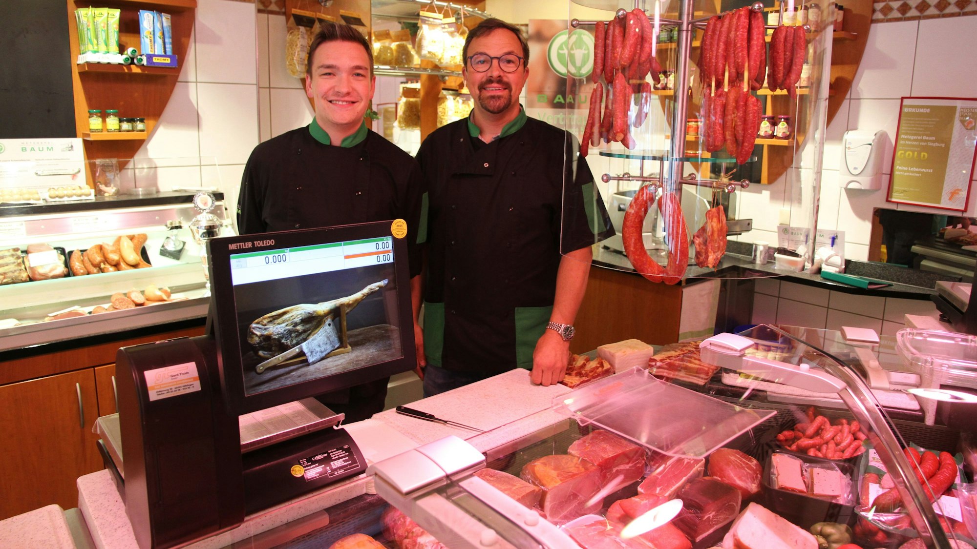 Zwei Männer hinter der Bedientheke einer Metzgerei.