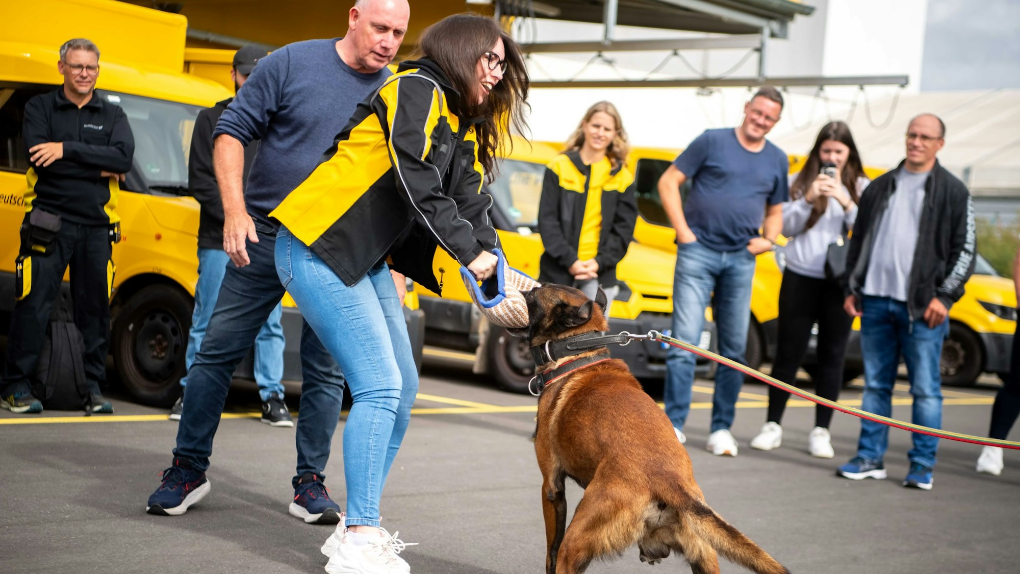 Eine Zustellerin hält das Kissen, in das der Hund Clip sich verbissen hat. Hinter ihr steht Martin Pfaff.