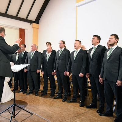 Ein Männerchor in dunklen Anzügen beim Auftritt.