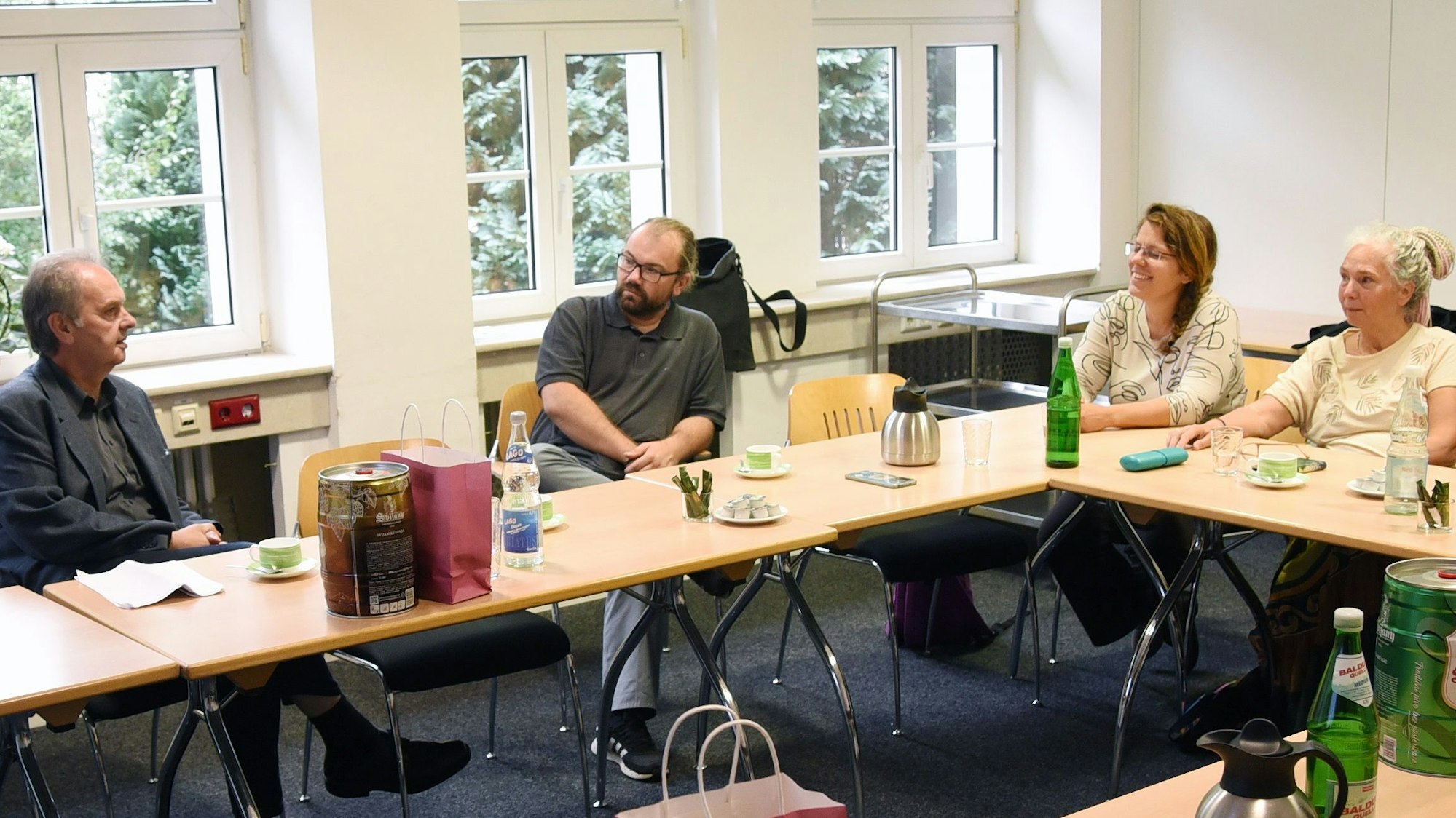 Zwei Männer und zwei Frauen sitzen an einem Tisch und tauschen sich aus.
