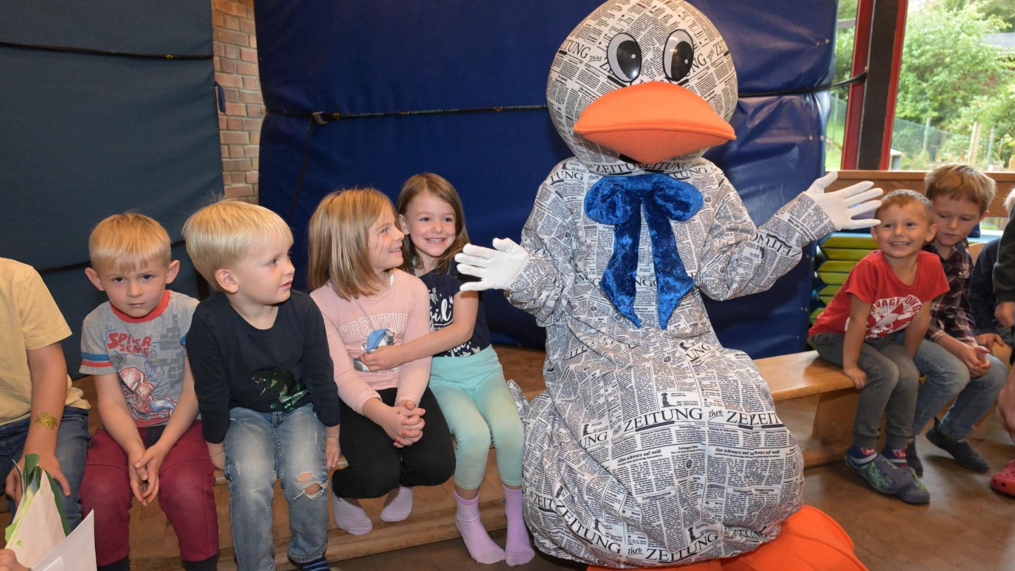 Paula Print sitzt in der KEO Kita Overath Eichenweg auf einer Bank zwischen Kindern.